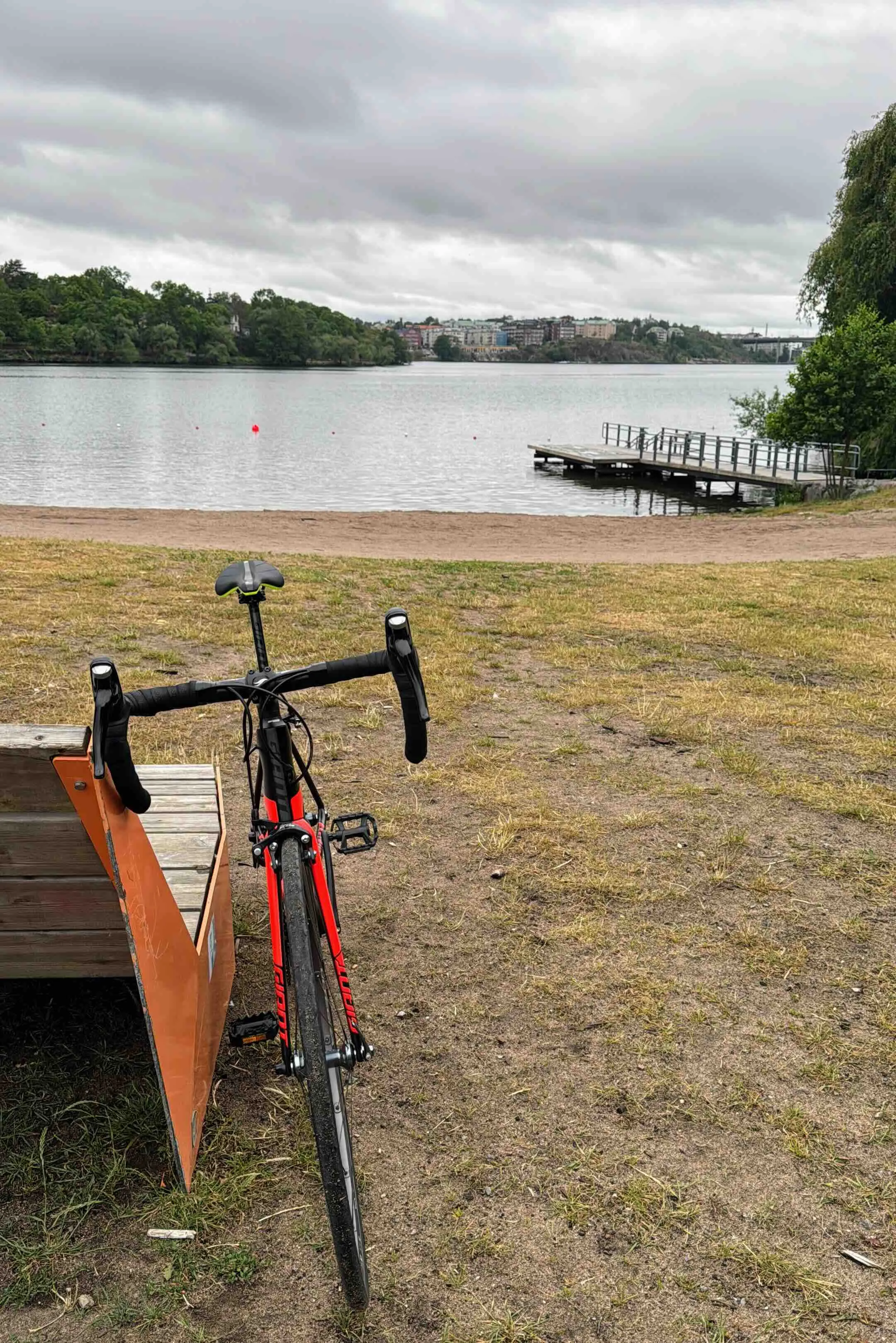 Bike in the forefront leaning on a bench with the sea in the back