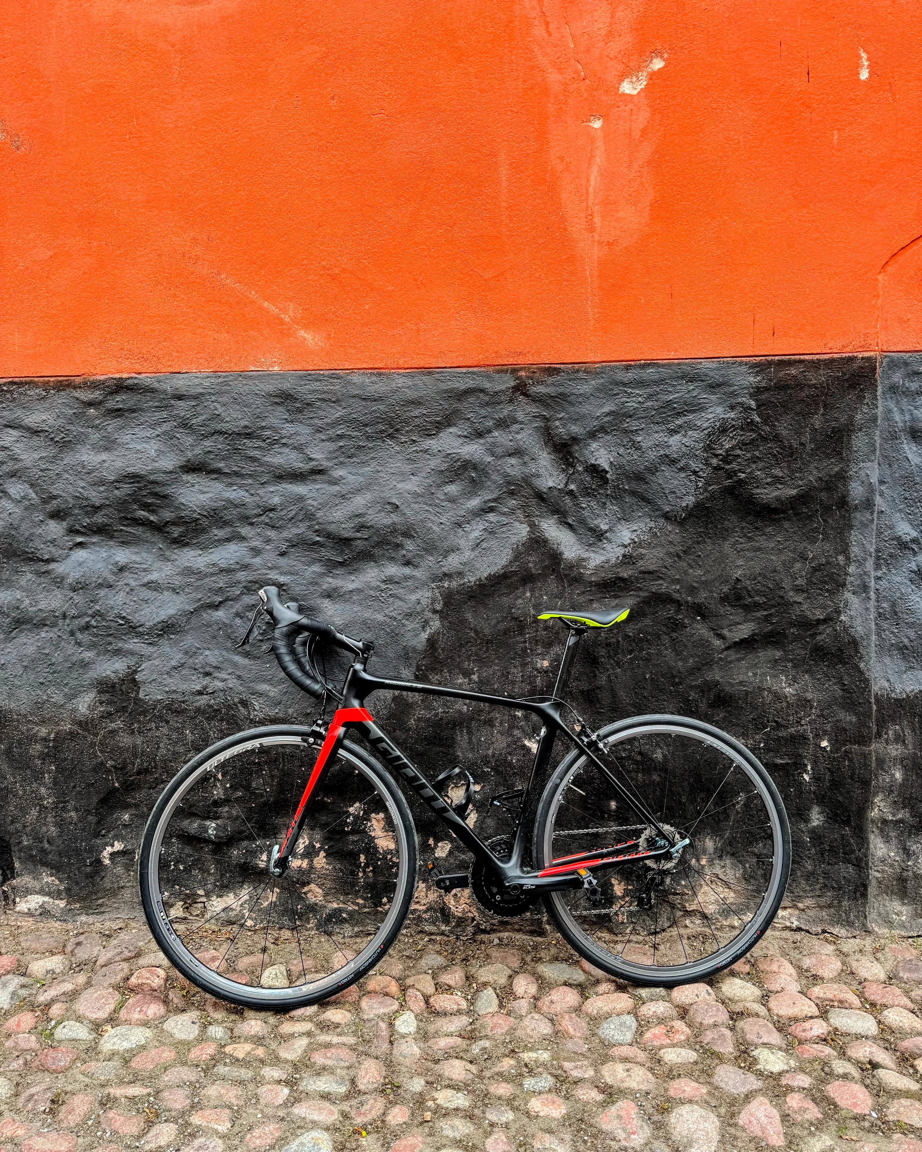 A Giant TCR Advanced 2 roadbike with a black and orange colour scheme standing against a black and orange wall
