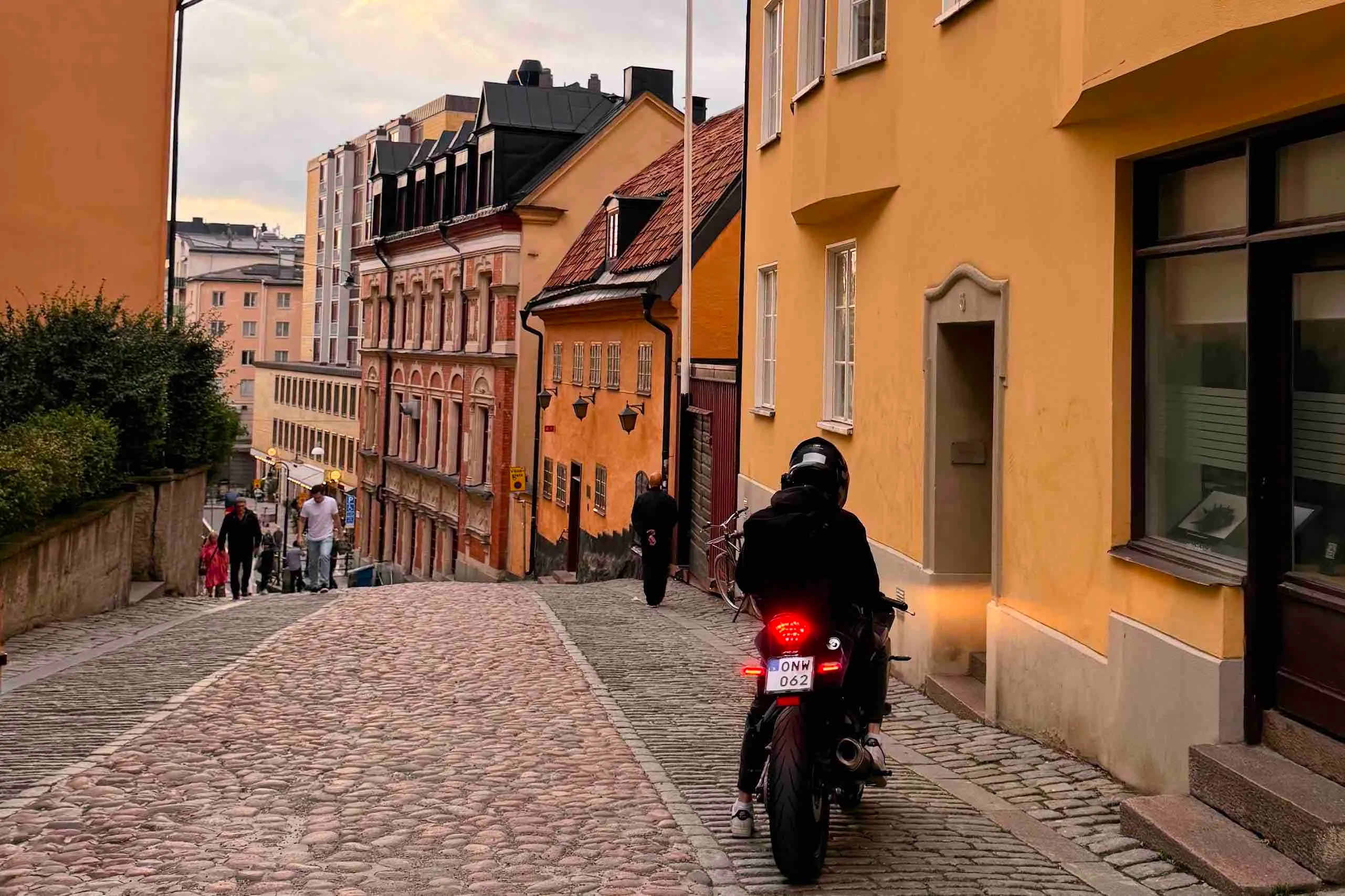 The back of a biker on a cobbled street going downhill